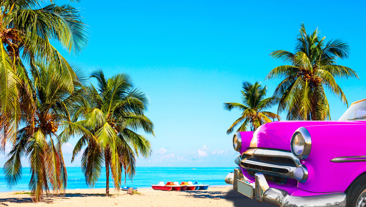 Strand in Kuba mit Palmen und einem alten rosa Auto