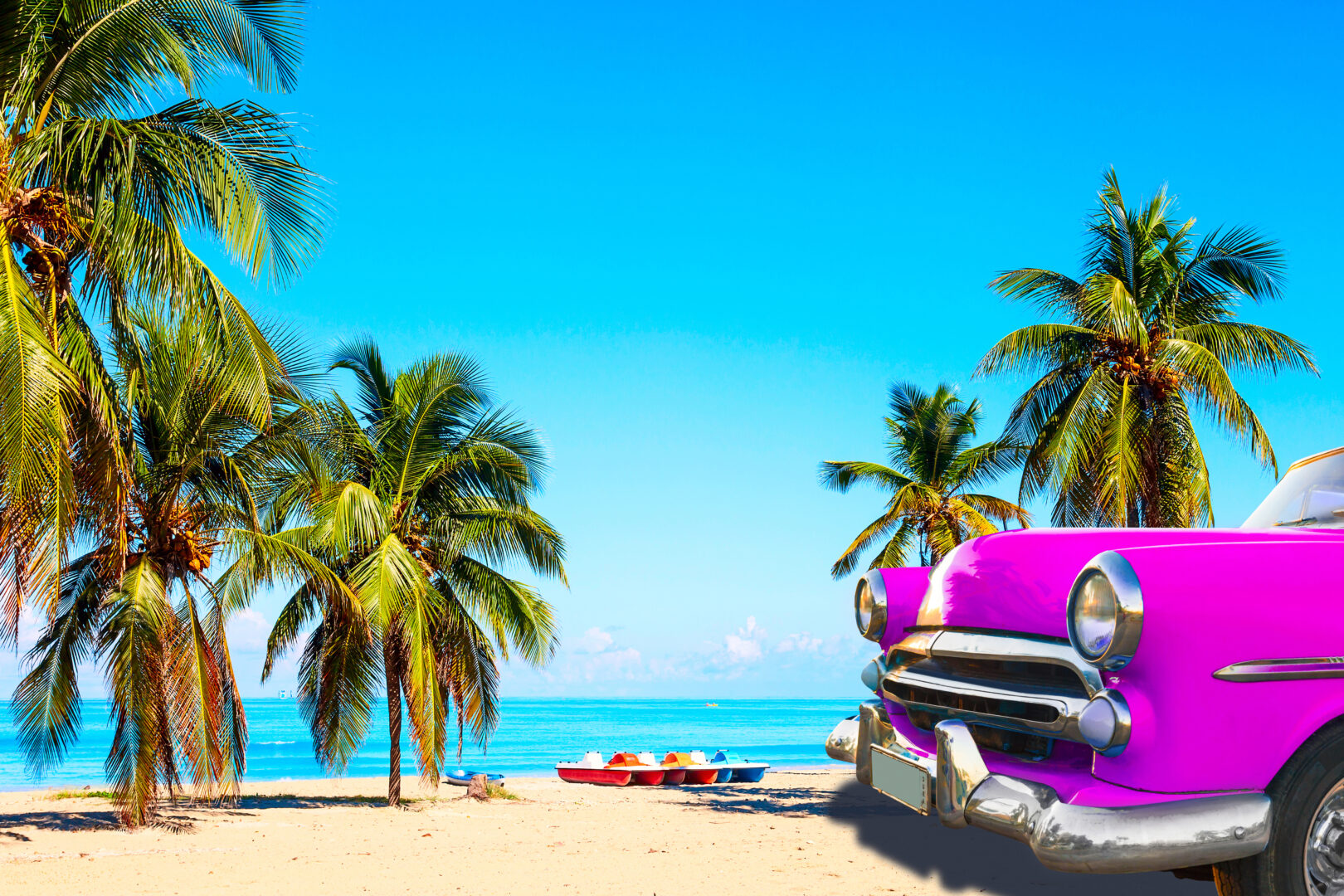 Strand in Kuba mit Palmen und einem alten rosa Auto